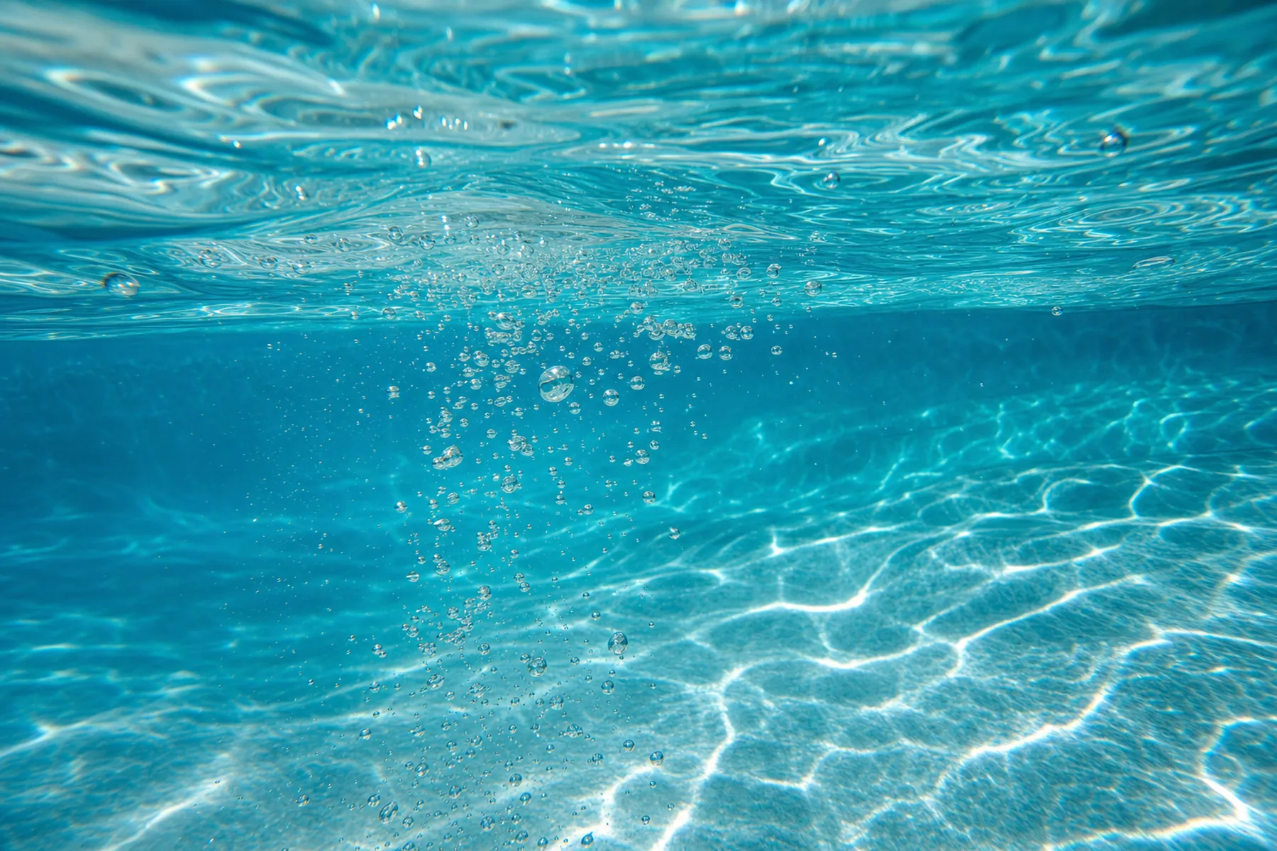 Macro photograph of clear pool water with sunlight caustics